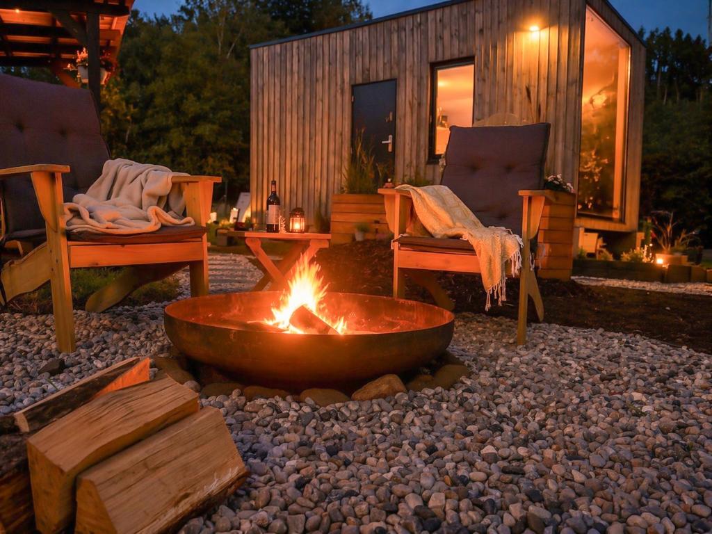 a fire pit in a yard with two chairs and a house at Tiny house u řeky - Bouda Krušnohorka in Vojkovice