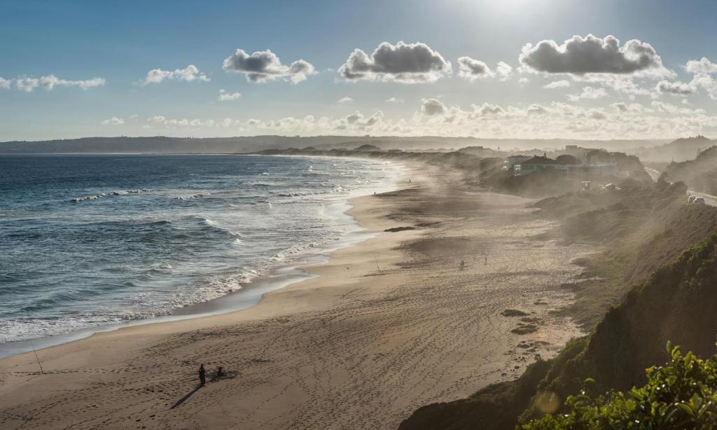 a beach with people on the sand and the ocean at Pearly Beach House in Plettenberg Bay