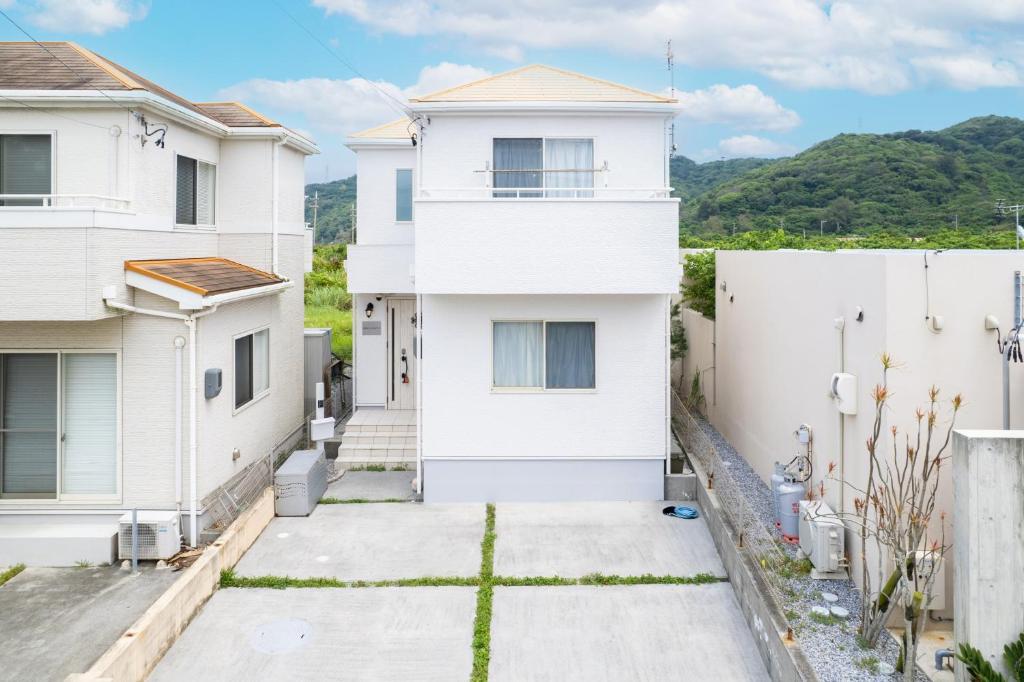 a white house with a fence at 古宇利島まで車で10分の星降るやんばるテラス海まで徒歩3分のは1棟貸 in Nago