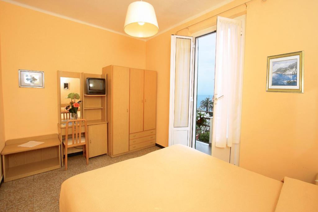 a bedroom with a bed and a desk and a window at Hotel Villa Bianca in Laigueglia