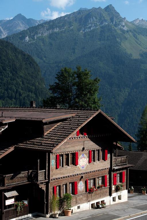 a building with red shutters and a mountain at Le Bois-Gentil in Gryon