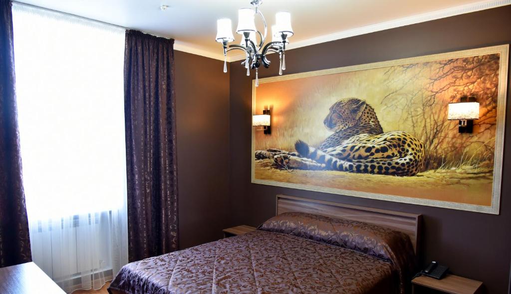 a bedroom with a bed and a large painting on the wall at Hotel Gloria in Kostanay