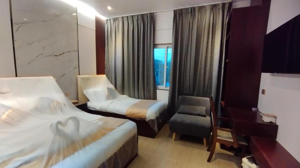 a hotel room with two beds and a chair at Selah Hotel Dipolog in Dipolog