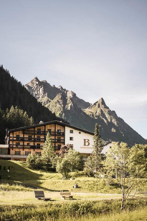 a large building with mountains in the background at Sporthotel Bachmann in Gargellen