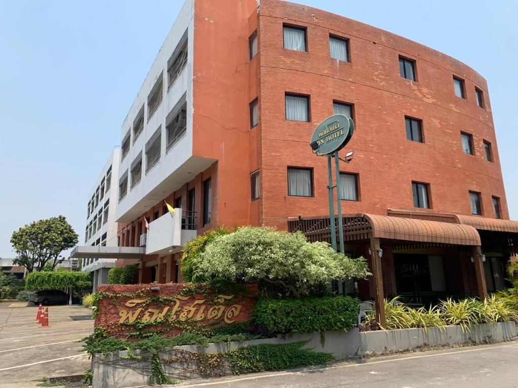 ein rotes Backsteingebäude mit einem Schild davor in der Unterkunft โรงแรมพิณ in Lampang