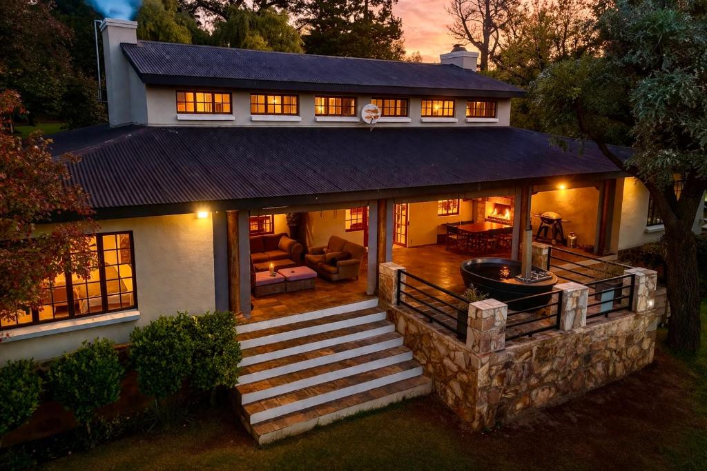 a large house with a porch and a staircase at Luxury Country Retreat Hot Tub & Farm Views in Dullstroom