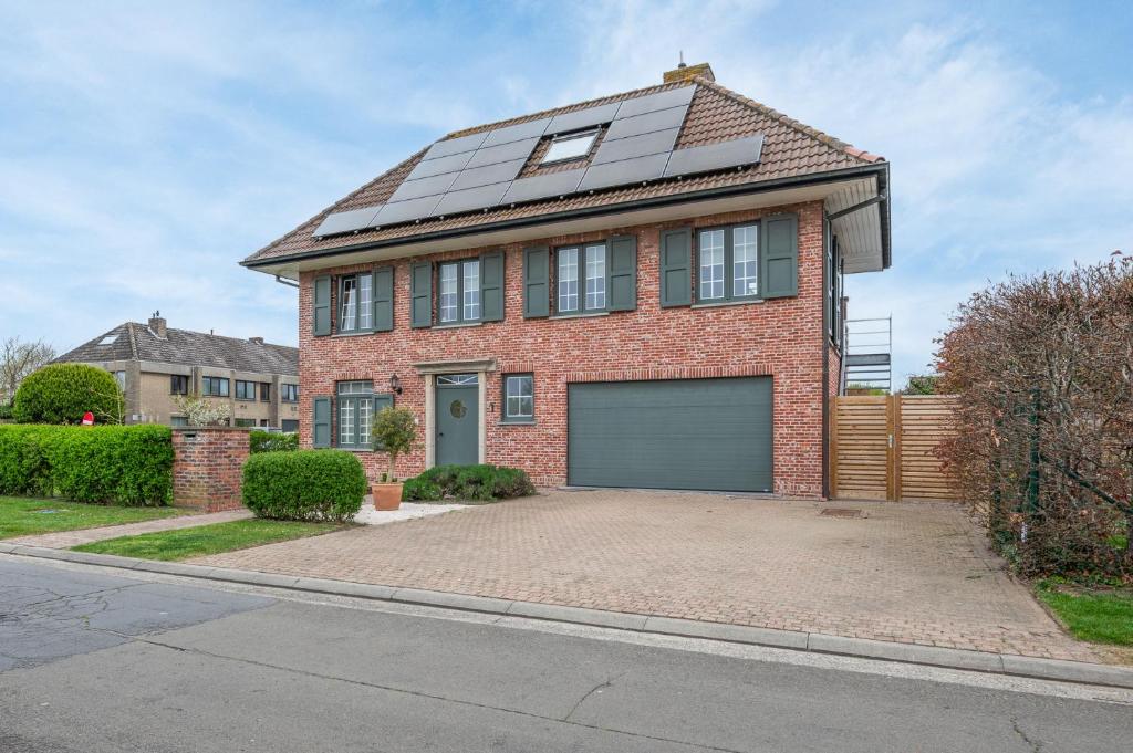 a red brick house with solar panels on the roof at Amazing villa for 8 in Bredene in Bredene