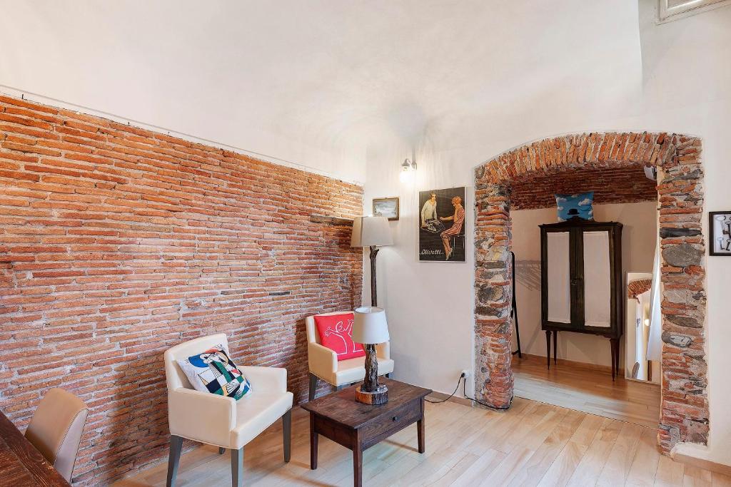 a room with a brick wall and two chairs and a table at La Volta Segreta in Albenga
