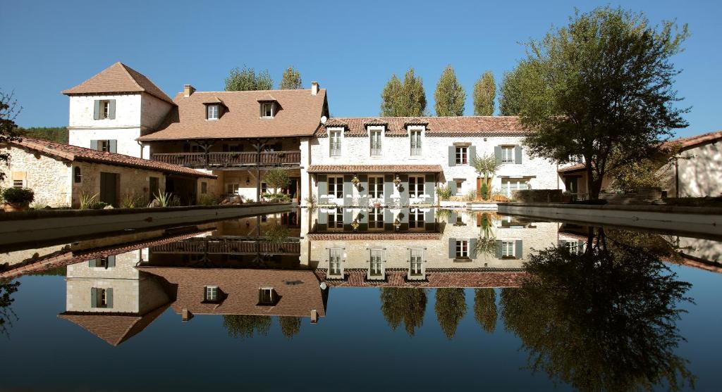 uma casa e o seu reflexo numa massa de água em Le Mas Des Bories - Grand Perigueux em Antonne-et-Trigonant