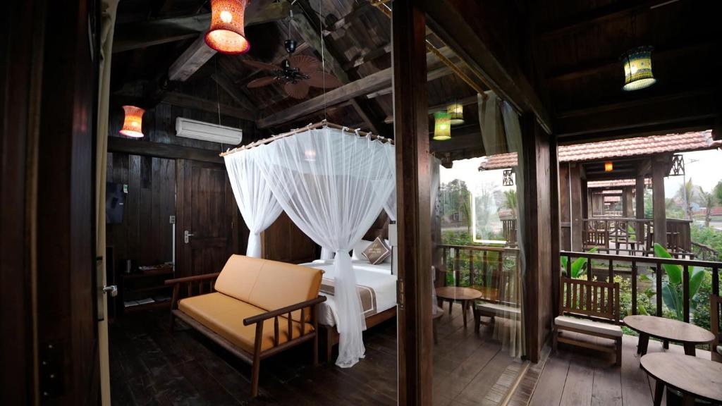 a room with a bed and an umbrella on a balcony at The Palm Tree Bungalow in Xuân Sơn