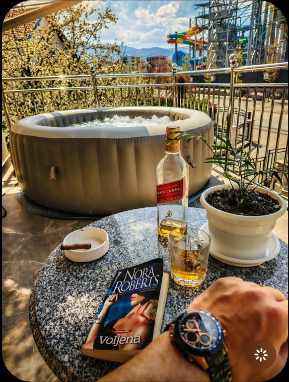 a bottle of whiskey sitting on a table next to a hot tub at Apartman Raj in Vrnjačka Banja