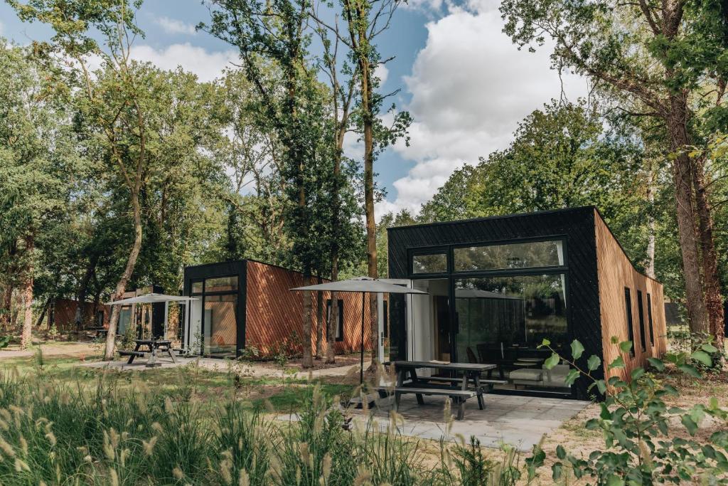 a house in the woods with a picnic table and benches at Summio Vakantiepark Schaijk in Schayk