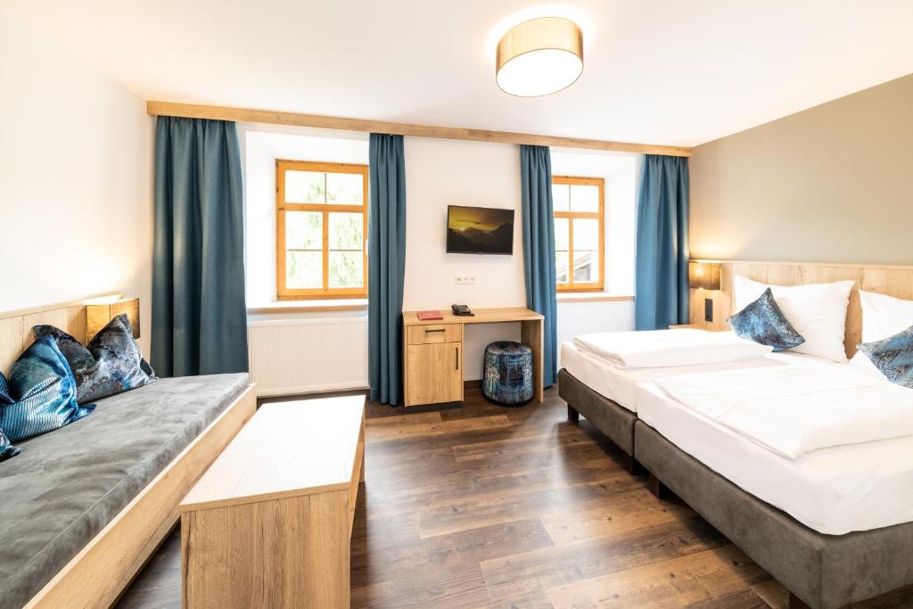 a hotel room with two beds and a desk at Hotel Heitzmann in Mittersill