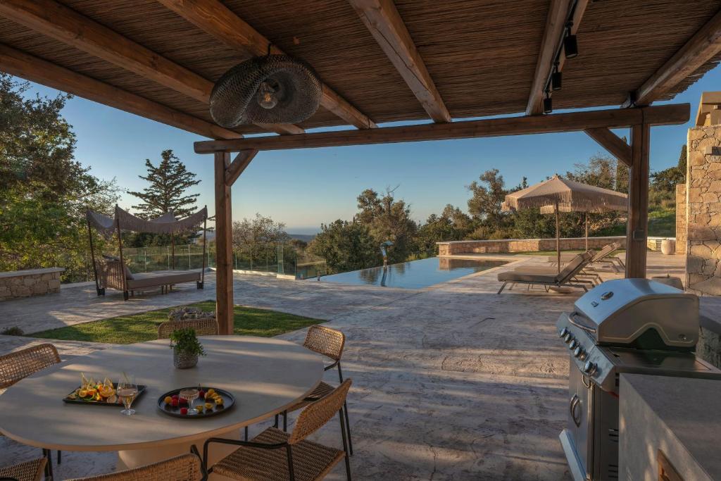 a patio with a table and a stove and a grill at Sunny Villa-Earthen Stone Gem by etouri in Margarítai