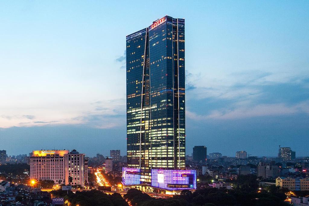 a tall building with lights on it in a city at Lotte Hotel Hanoi in Hanoi