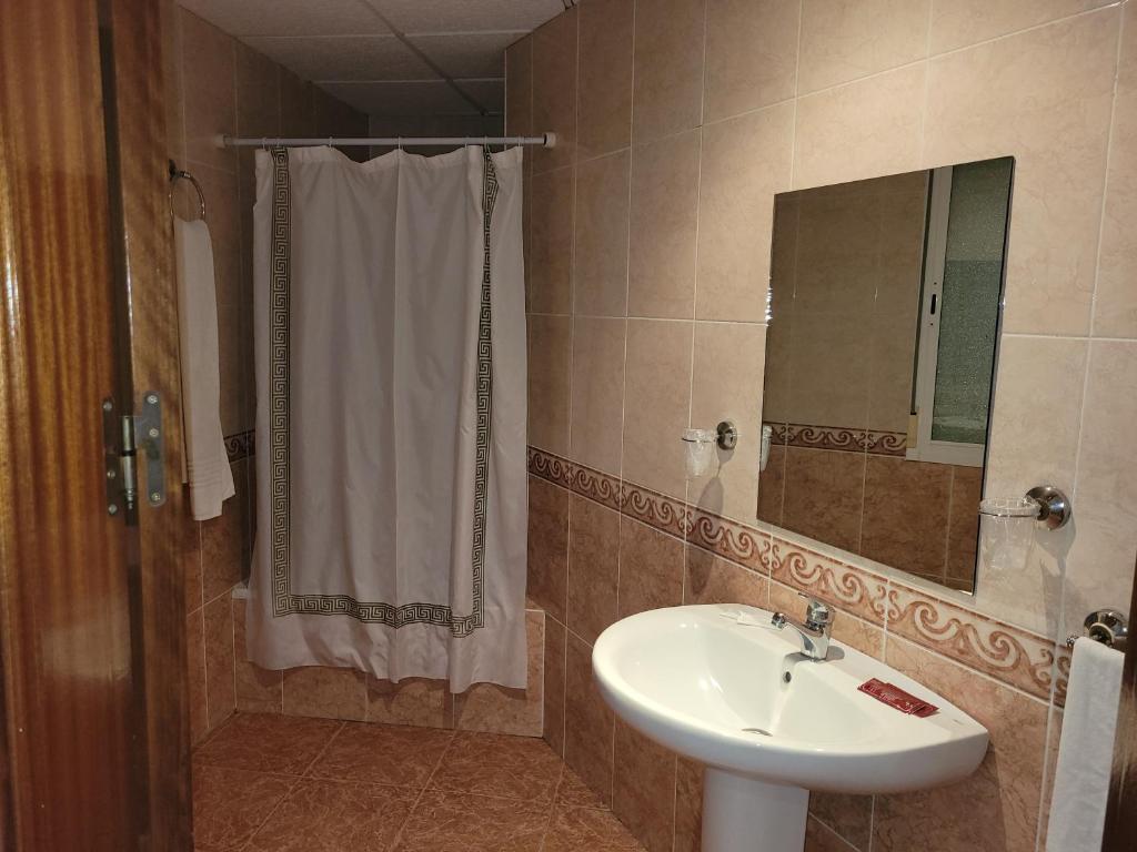 a bathroom with a sink and a shower curtain at Hostal La Perla in Zalamea de la Serena