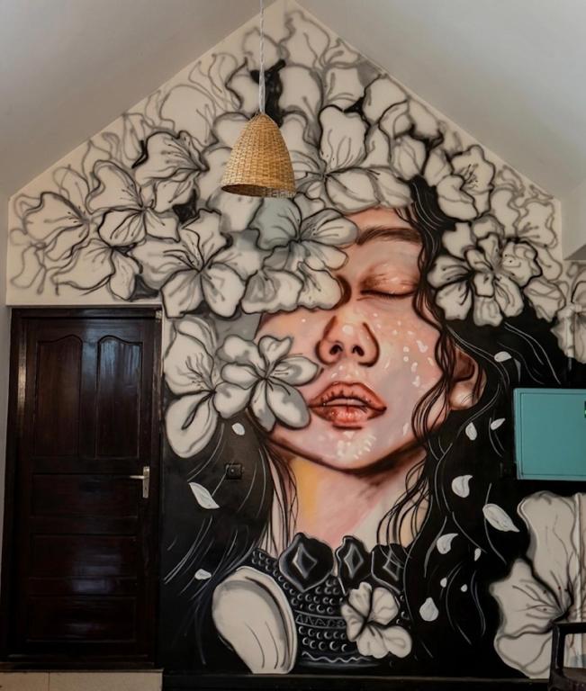 a mural of a woman with flowers on a wall at Villa Mud Apple in Varkala