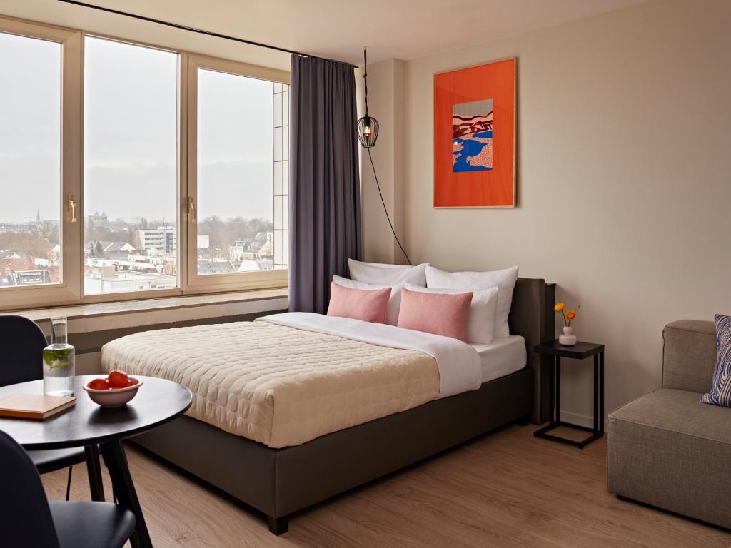 a bedroom with a bed with pink pillows and a table at Numa Cologne Ehrenfeld in Cologne