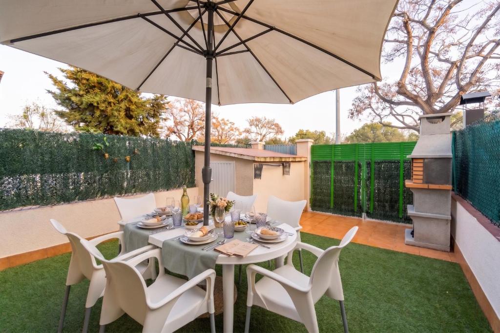 a table and chairs with an umbrella in a garden at Mediterranean Way - Ca l Ebre in Cambrils
