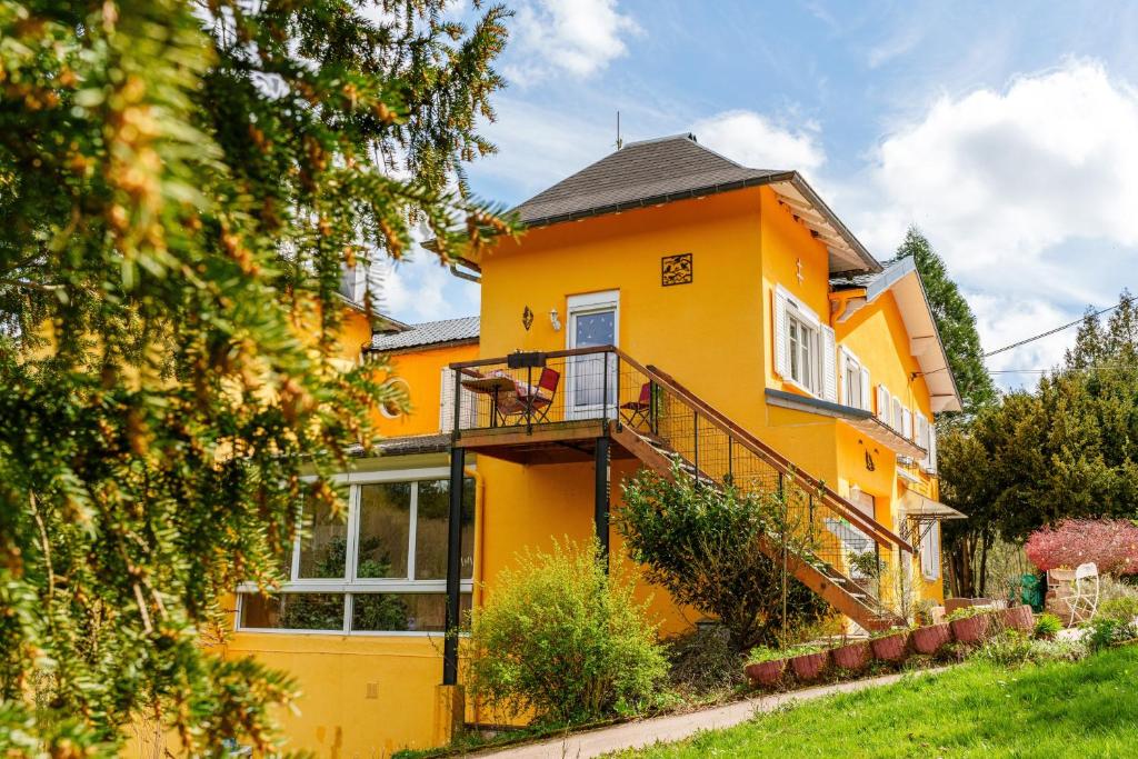 a yellow house with a balcony at Gîte forestier du Moulin - 10 pers in Raon-sur-Plaine