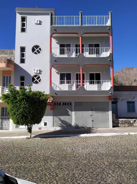 a white building with a tree in front of it at Casa Cabral : Big Apartment next to the beach in Tarrafal