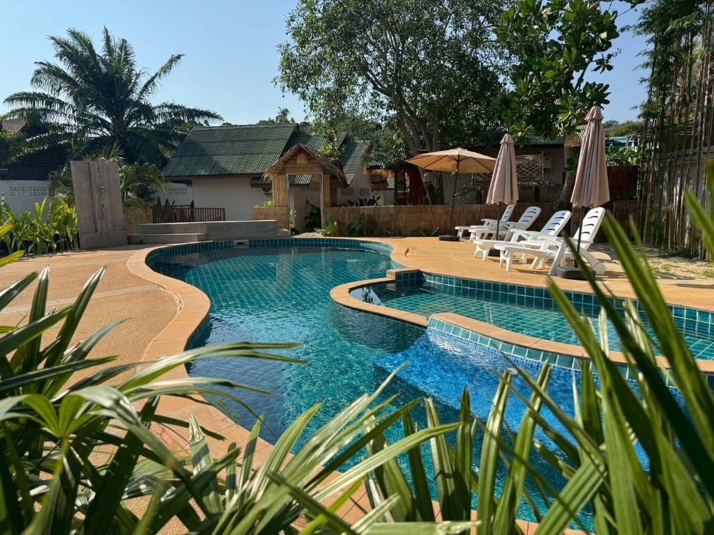 a pool with chairs and umbrellas in a yard at Tree Space Lanta Pool Stay Quiet & Near Beach in Ko Lanta