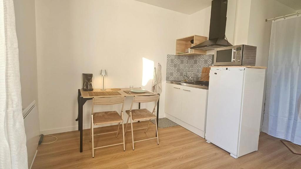 a kitchen with a table and a white refrigerator at Studio Indépendant au calme in Cugand