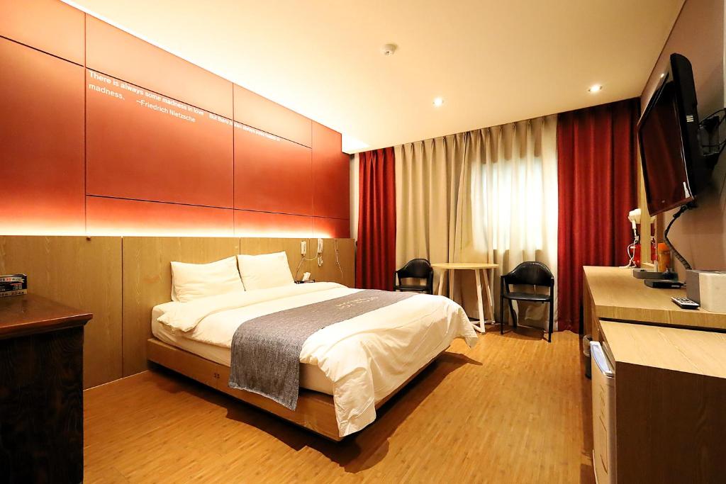 a hotel room with a bed and a flat screen tv at Ingye Joy Hotel in Suwon