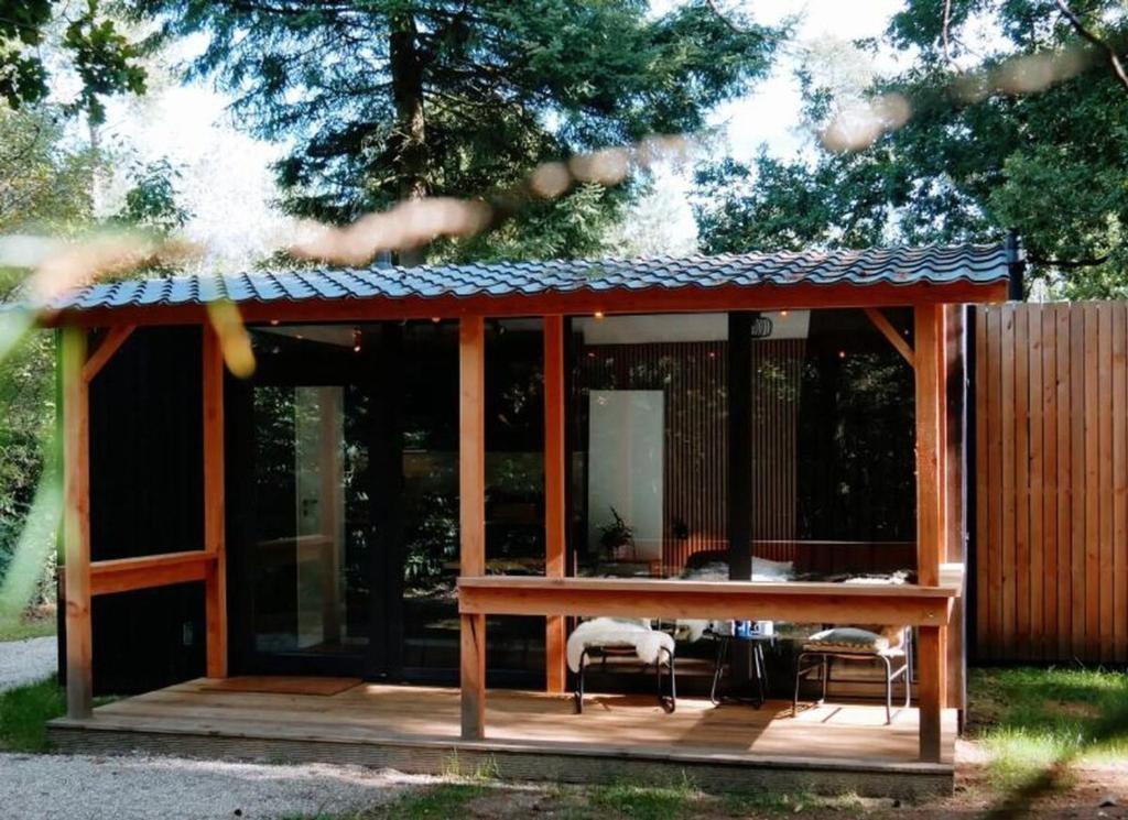 a pavilion with a table and chairs on a deck at Outdoors Holten - Forest Cabin in Holten