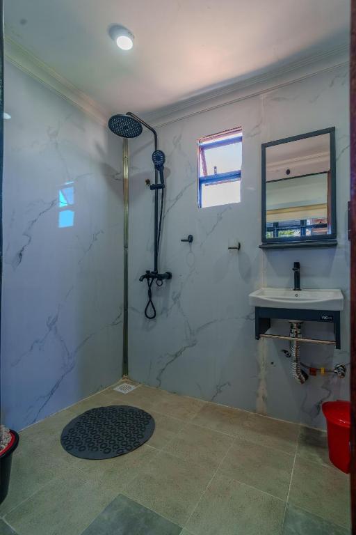 a bathroom with a shower and a sink and a mirror at Mayas Stay in Busia