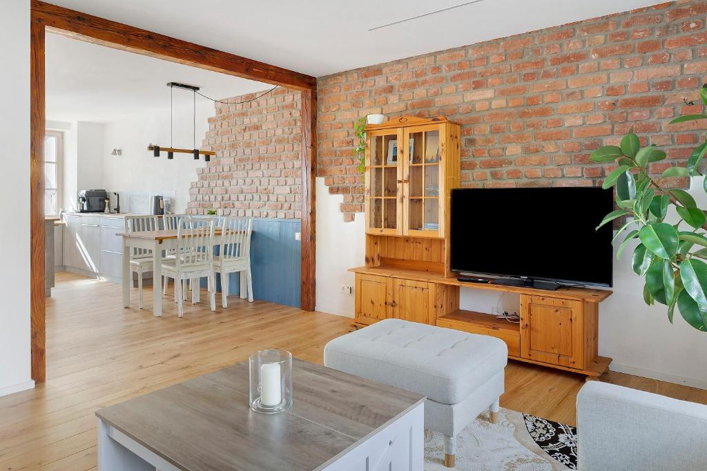 a living room with a brick wall and a flat screen tv at Feierabend am Kaiserstuhl in Bötzingen