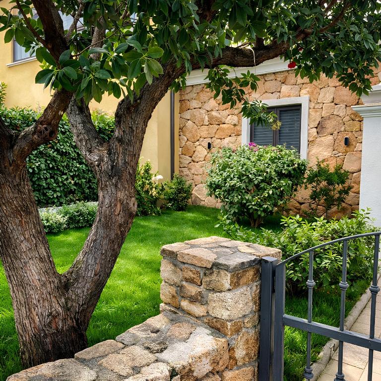 a tree and a stone wall in front of a house at Casa Marisella in San Teodoro