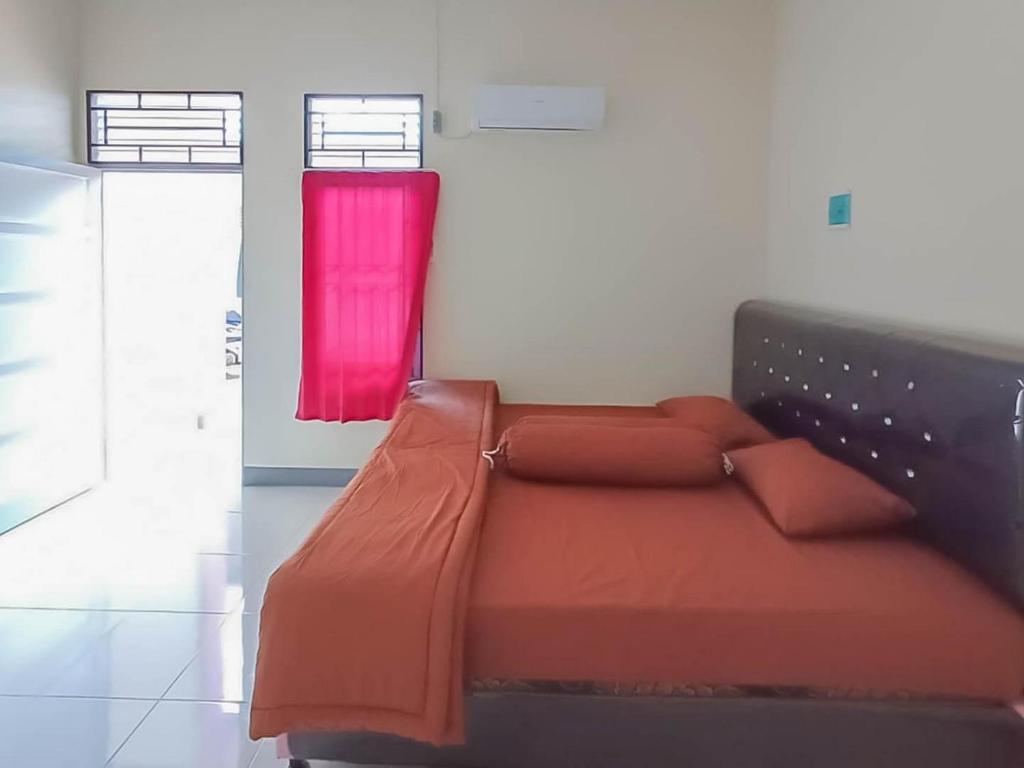 a bedroom with a bed with a red blanket at Verisha Inn Singkawang RedPartner in Singkawang