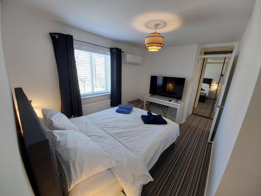 a bedroom with a white bed and a television at 2 beds, AC, fully enclosed patio, private parking in Poole