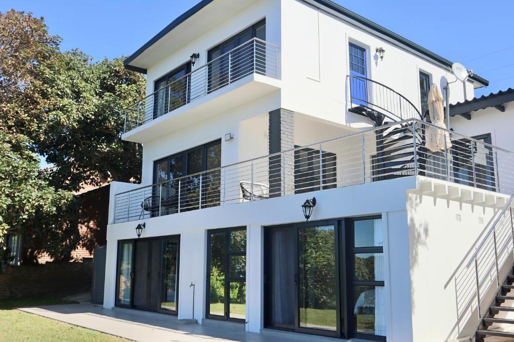 a white house with large windows and balconies at Chintsa Oceanfront in Chintsa