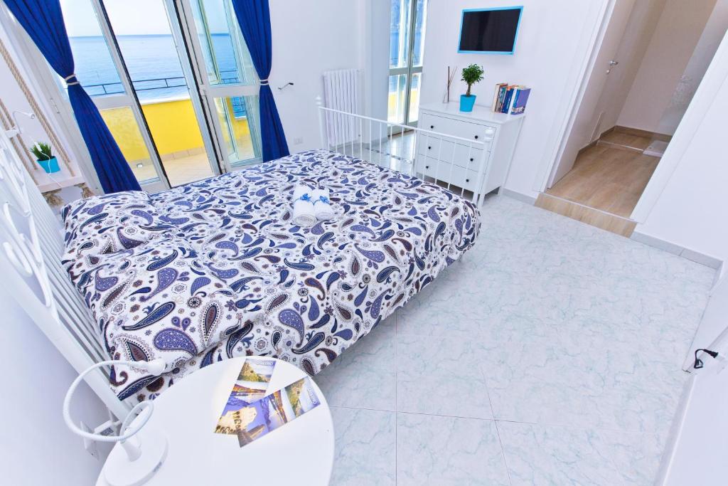 a bedroom with a bed with a blue and white bedspread at On the beach Sea-view&Kitchen In Room in Salerno