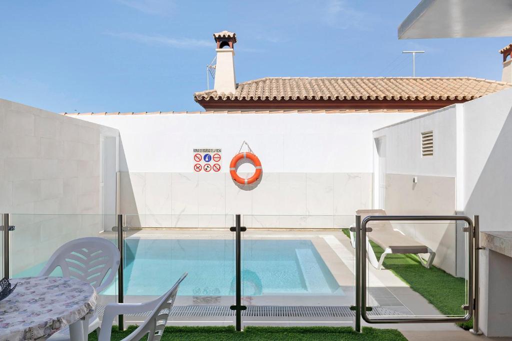 a swimming pool with a table and chairs next to a building at Casas Las Arenas 2 in Conil de la Frontera
