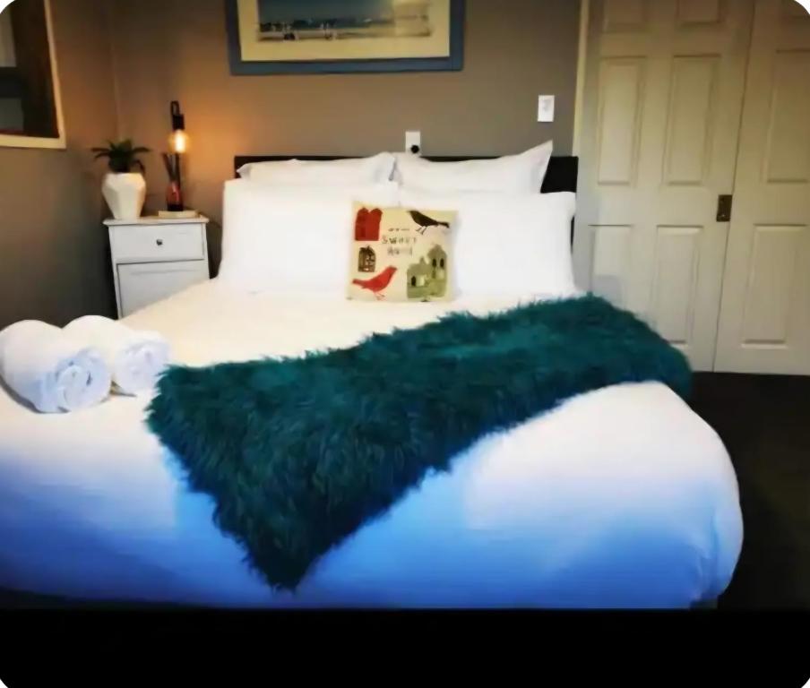 a bedroom with a bed with a green blanket on it at Tiki Hut in Tauranga
