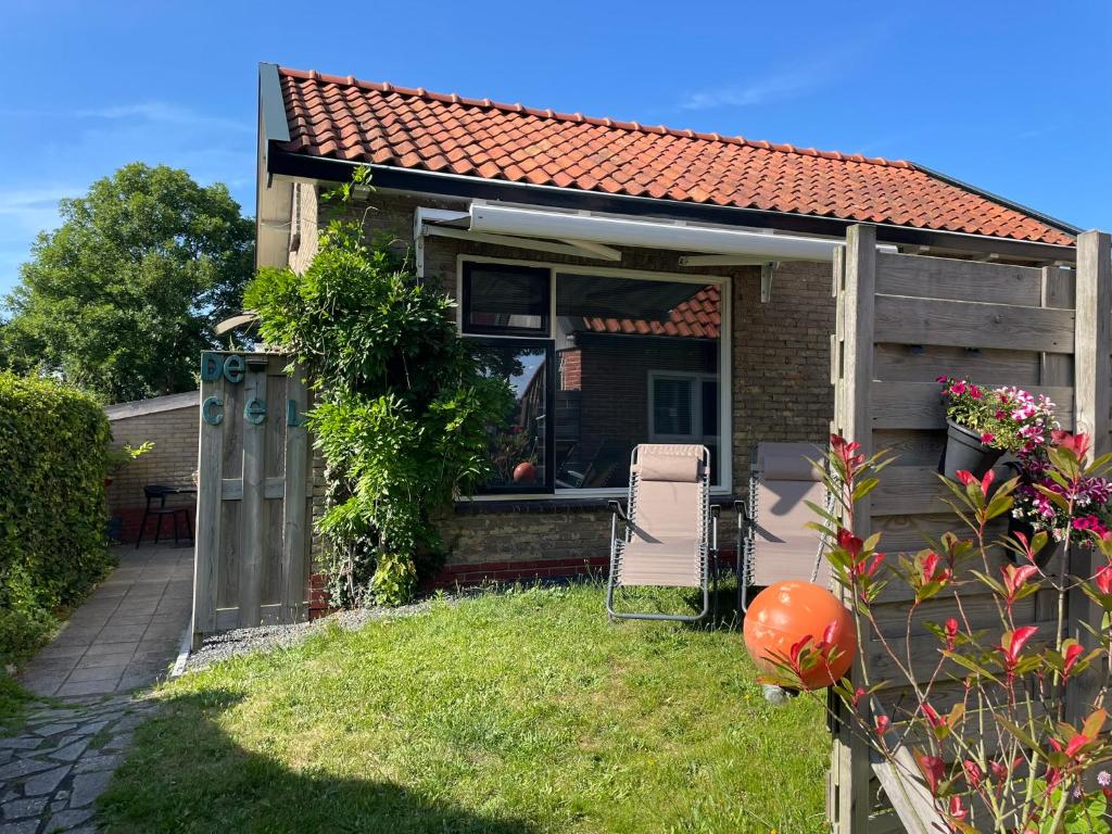 a small house with a patio and chairs in the yard at De Cel in Nes