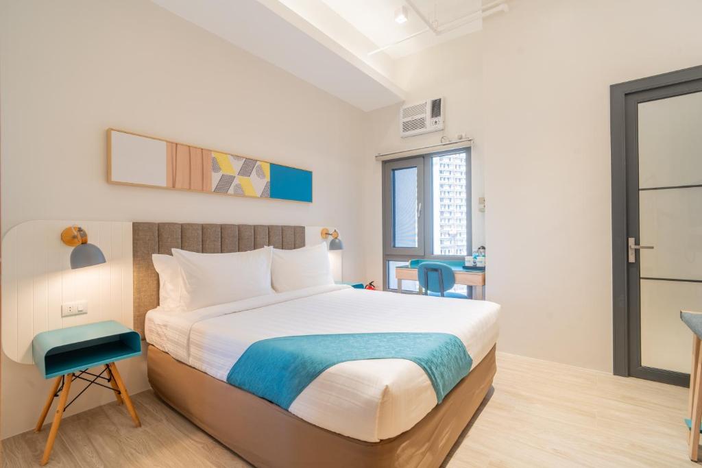 a bedroom with a large bed and a desk at ABC Plus Hotel & Homes in Cebu City