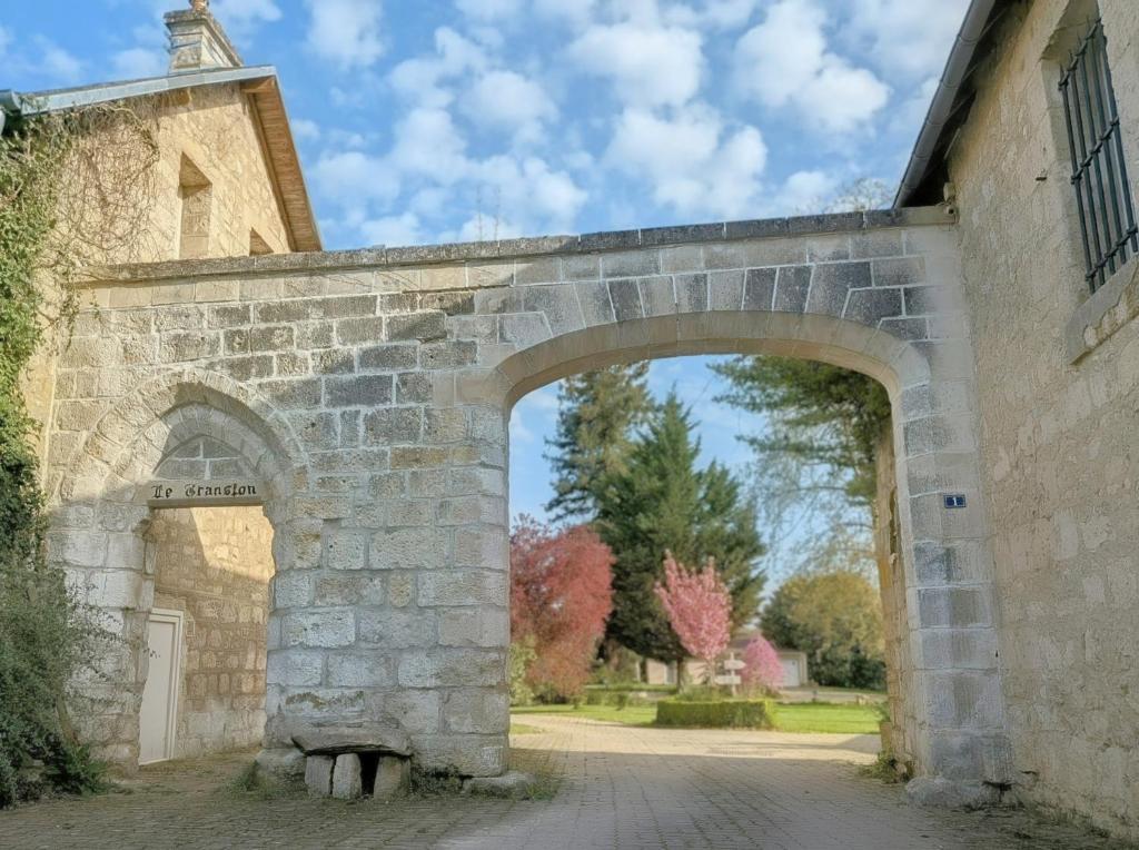 an archway in a stone wall with a building at Domaine Le Translon in Saint-Pierre-Aigle