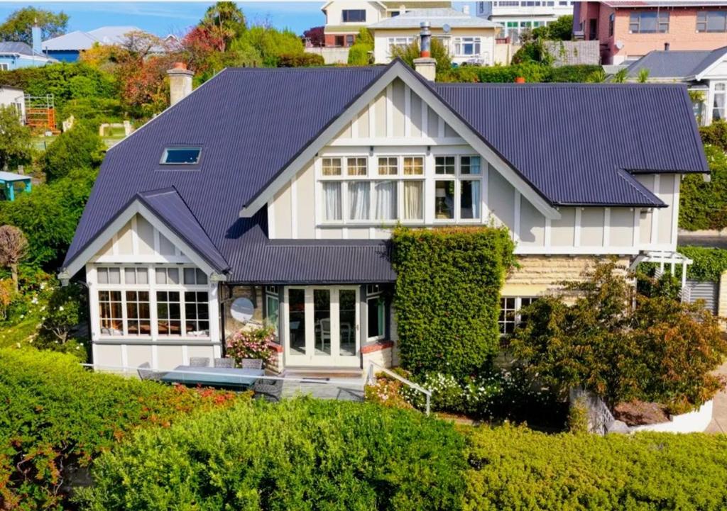 a white house with a blue roof at The Terrace - Luxury Villa in the heart of Oamaru in Oamaru