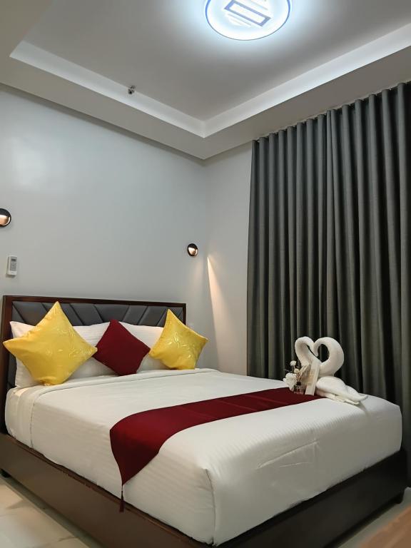 a bedroom with a large bed with yellow and red pillows at KJSGrandeInn in Manolo Fortich
