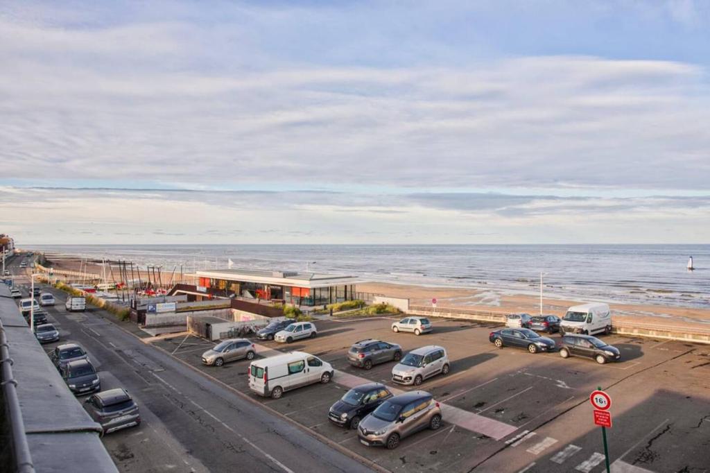 a parking lot next to the beach with cars parked at Appartement moderne, vue mer in Luc-sur-Mer