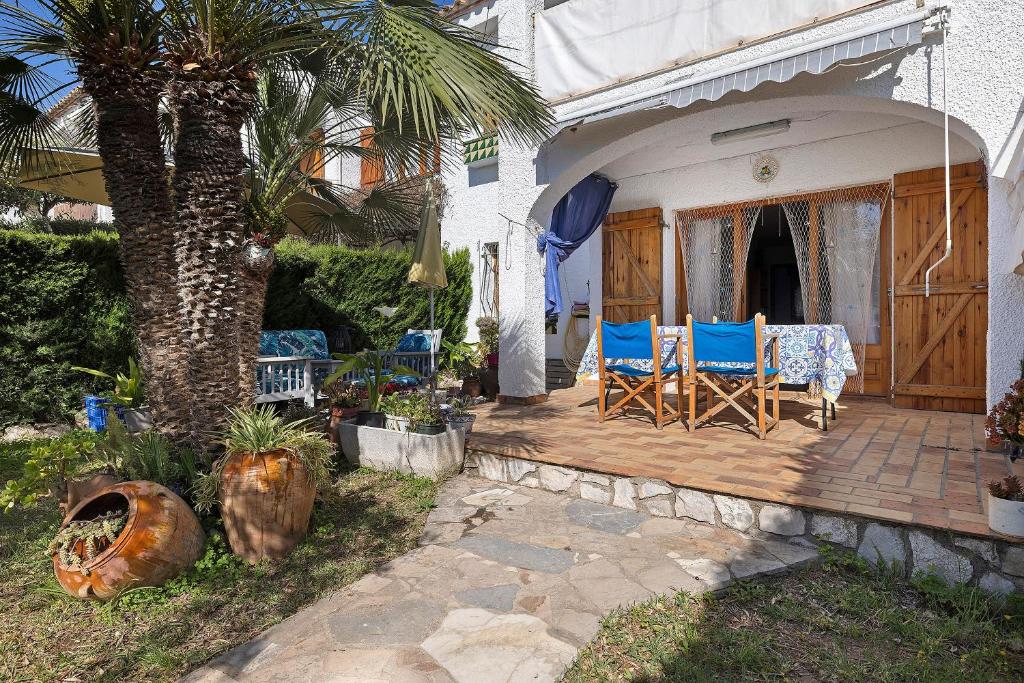 a patio with blue chairs and a palm tree at Casa Abril in L'Ampolla