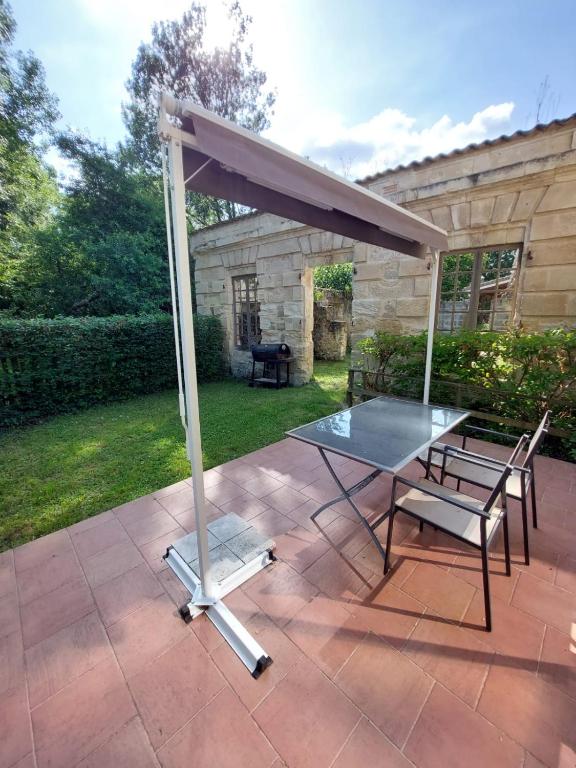 a table and chairs under an umbrella on a patio at Gîte Rabanier in Saint-Ciers-dʼAbzac