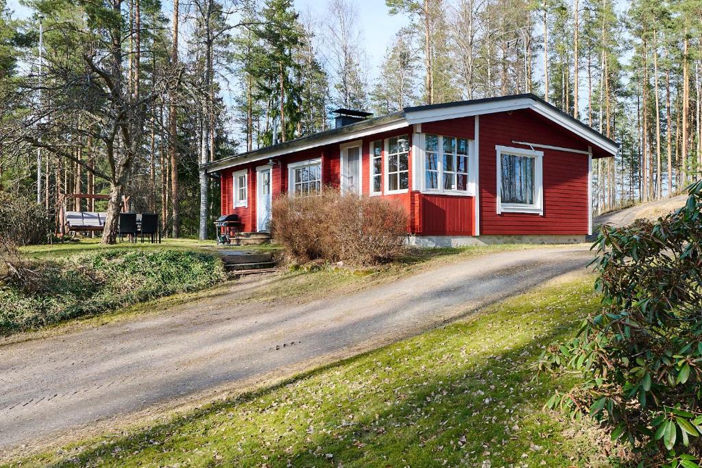 a red house on the side of a dirt road at Holiday Cabin Kukkula - AC, fireplace & wood-fired sauna in Porvoo