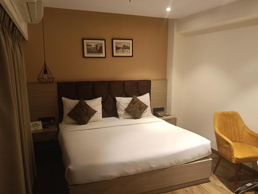 a bedroom with a large bed and a chair at Safa residency hotel in Perintalmanna