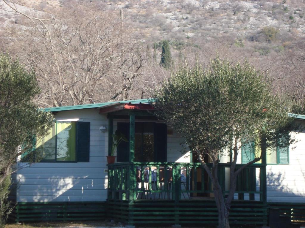 uma casa branca com um alpendre com árvores em frente em Mobile Homes Vila Punta em Šibuljina