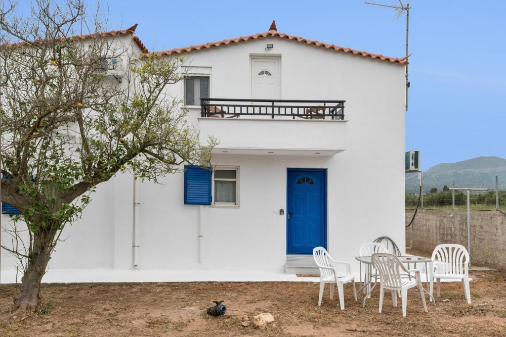 a white house with a blue door and a table and chairs at Angelina's Cute House in Neapoli Voion